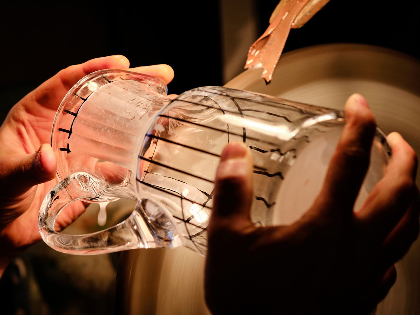 An artisan carefully engraving a glass mug.