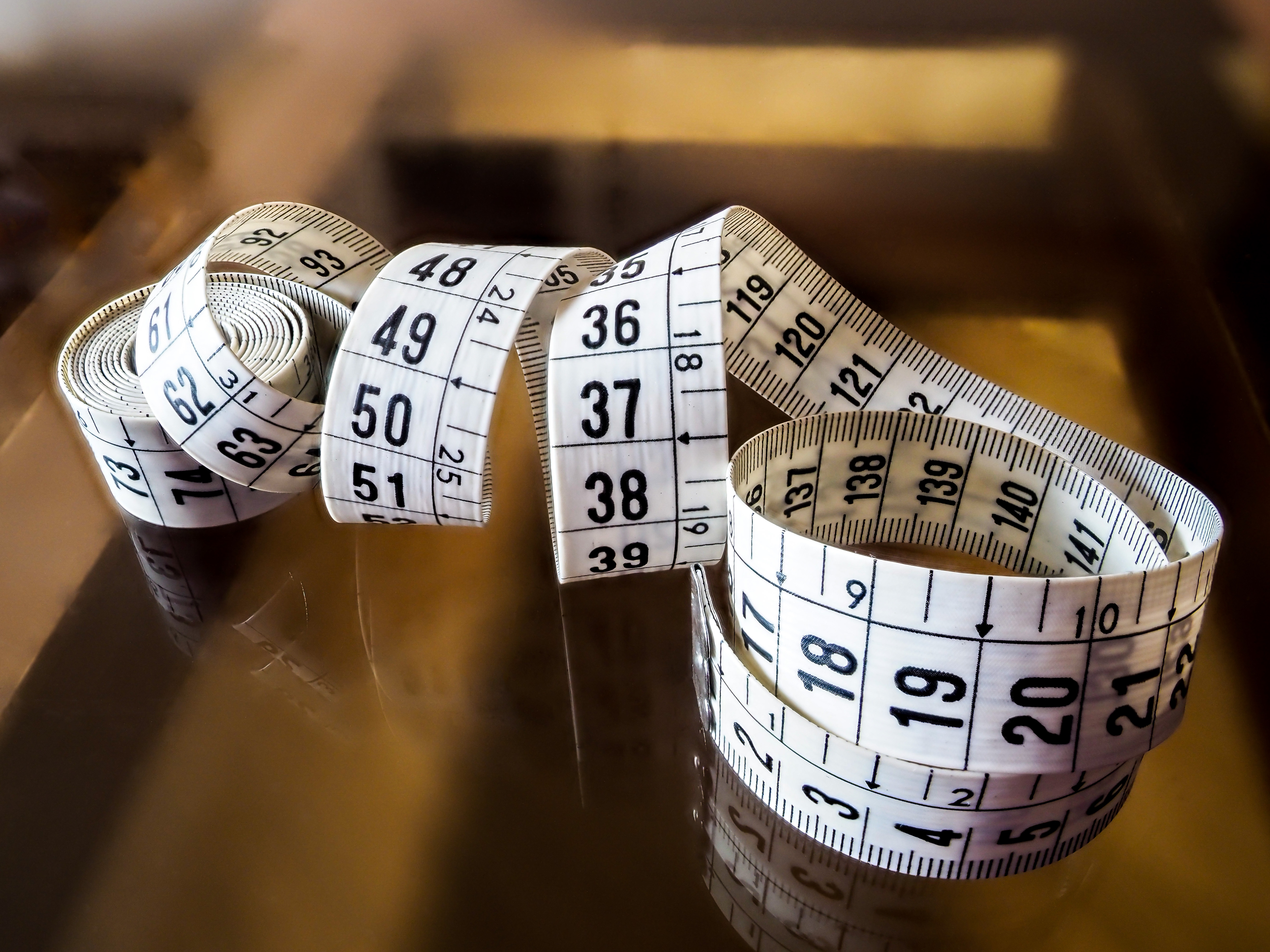 A tape measure curled on a reflective surface.